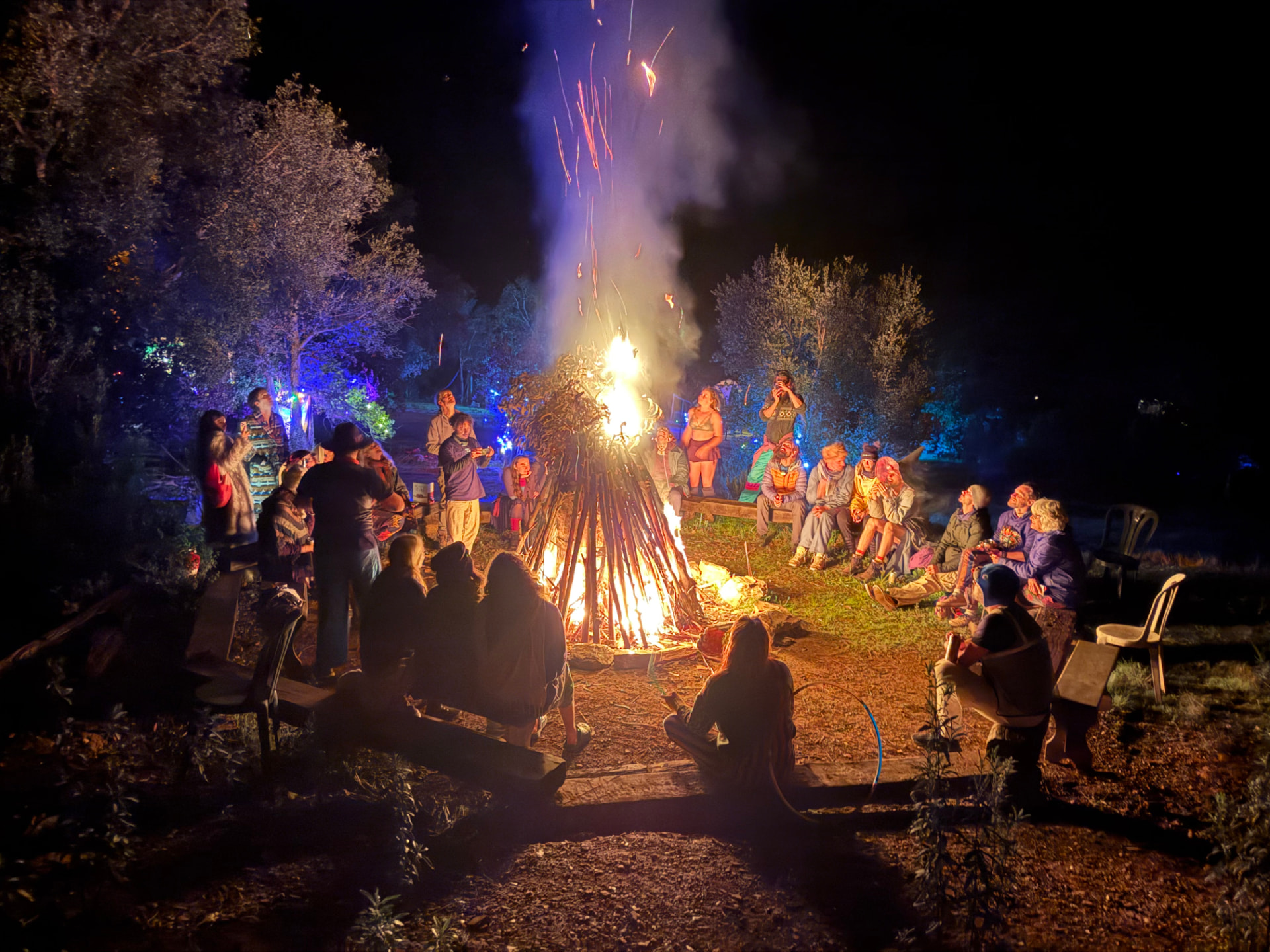 The effigy alight at night with the camp gathered in a circle around it