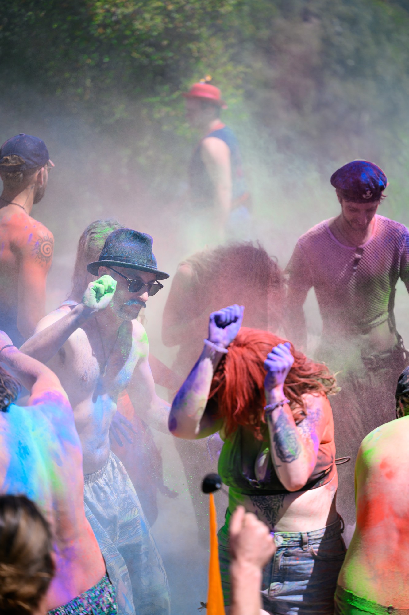 A sunlit crowd in a cloud of coloured powder